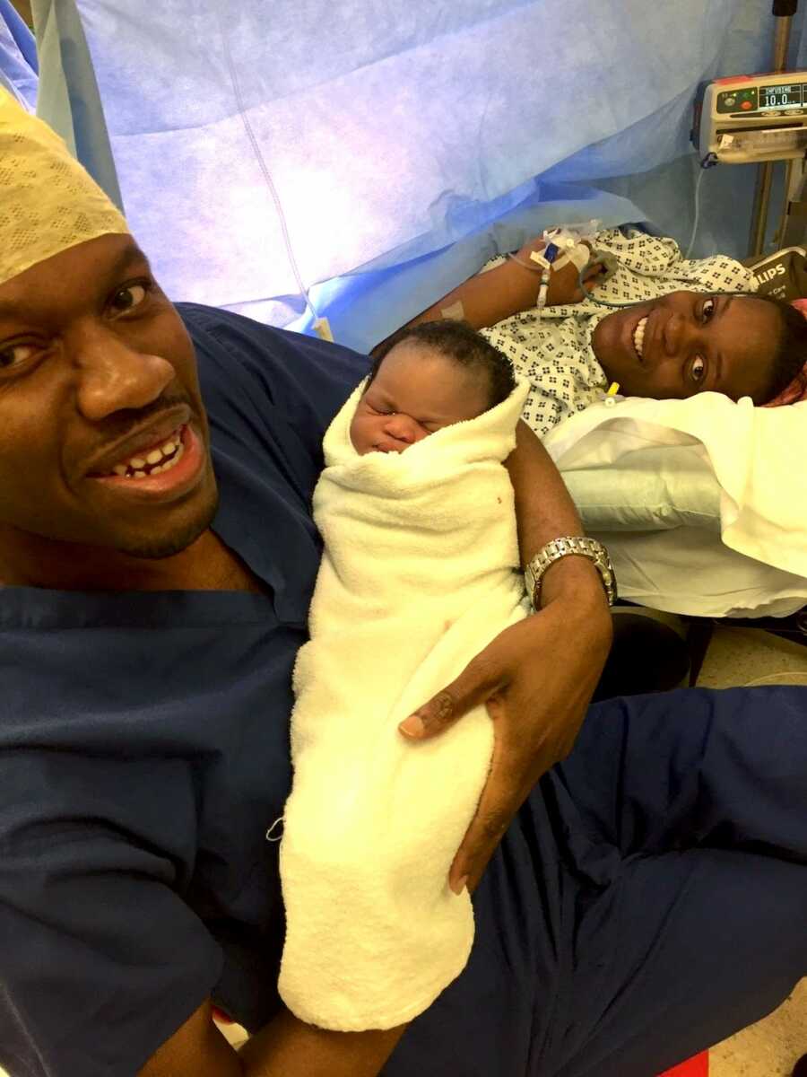 Couple take a selfie with their newborn child as the mom lays on the operating table from her C-section