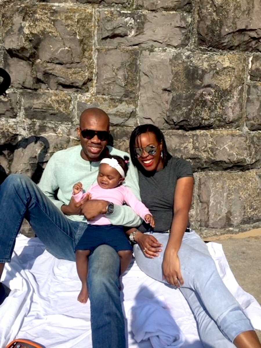 Family of three enjoy an outing together in the sunshine while sitting on a blanket