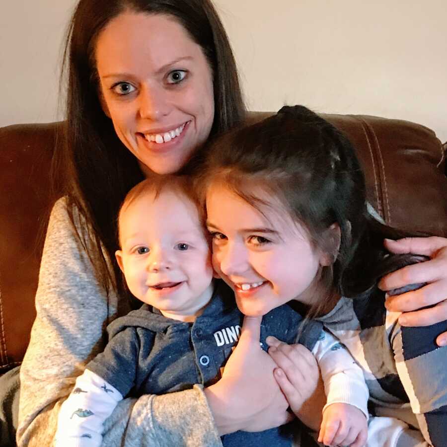 A mom sits with her two kids on the couch