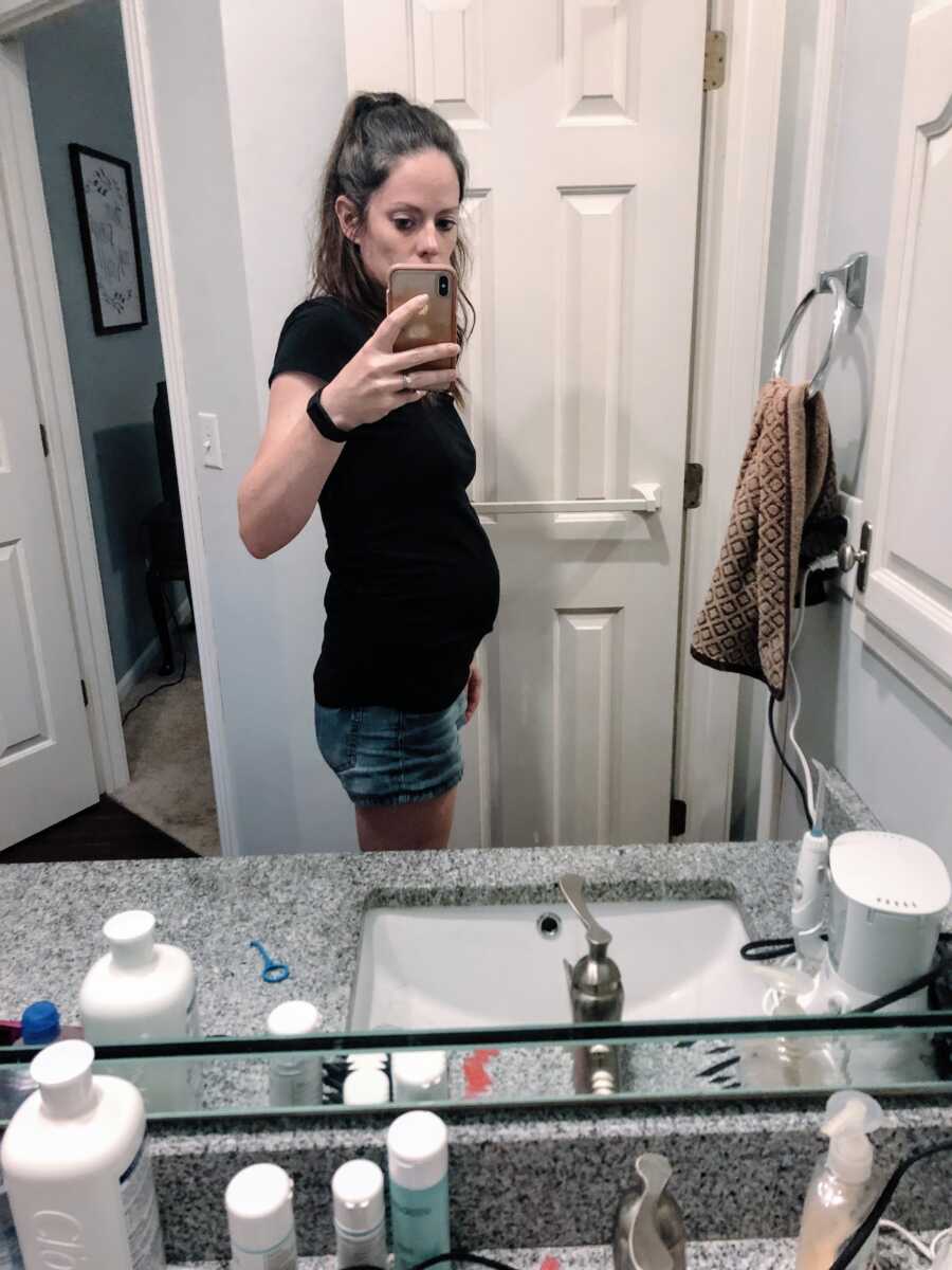A pregnant mom takes a picture of herself in the bathroom mirror