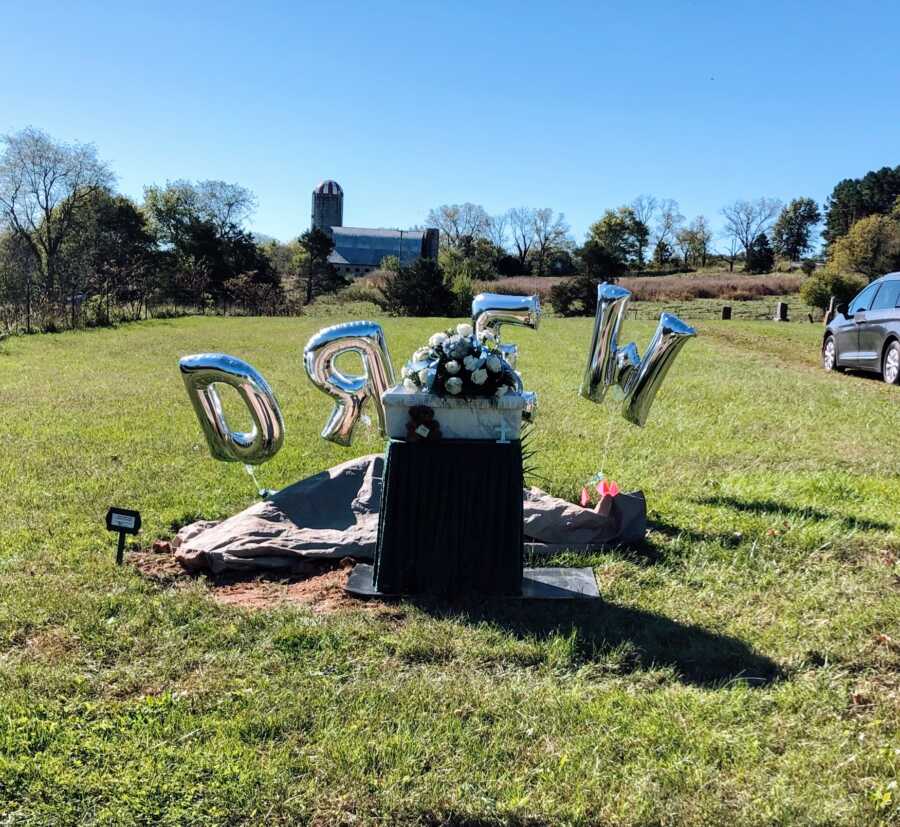 A baby's grave with balloons spelling his name: Drew