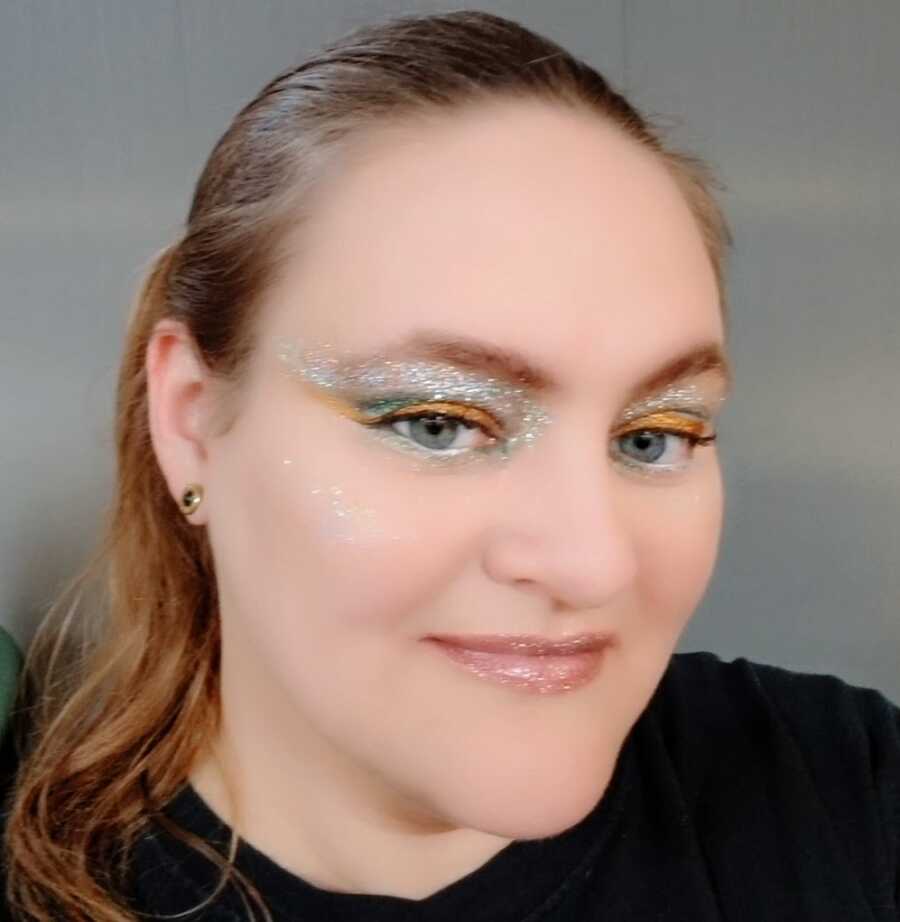 A woman with CRPS wearing glitter eyeshadow and a black shirt