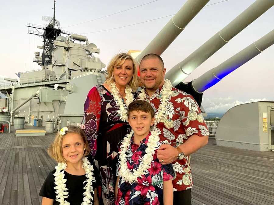 family stands on a navy ship wearing leis