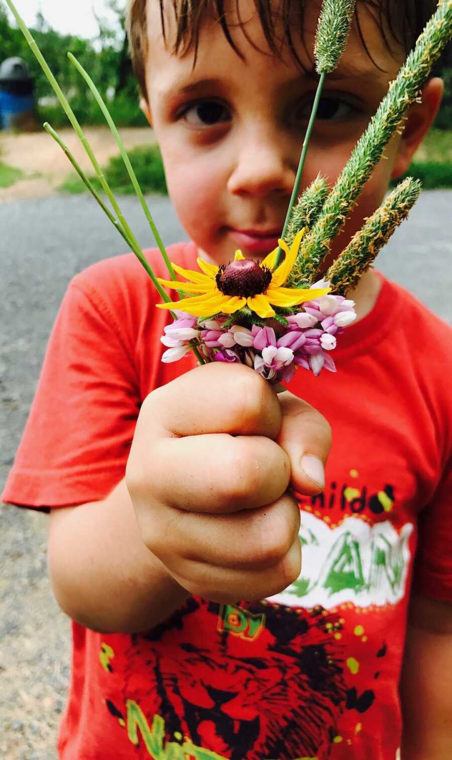 young boy holds a small bunch of flowers