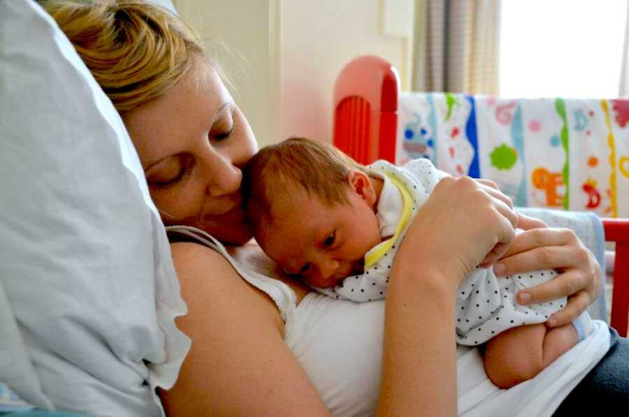 mother holds her newborn baby on her chest, admiring him