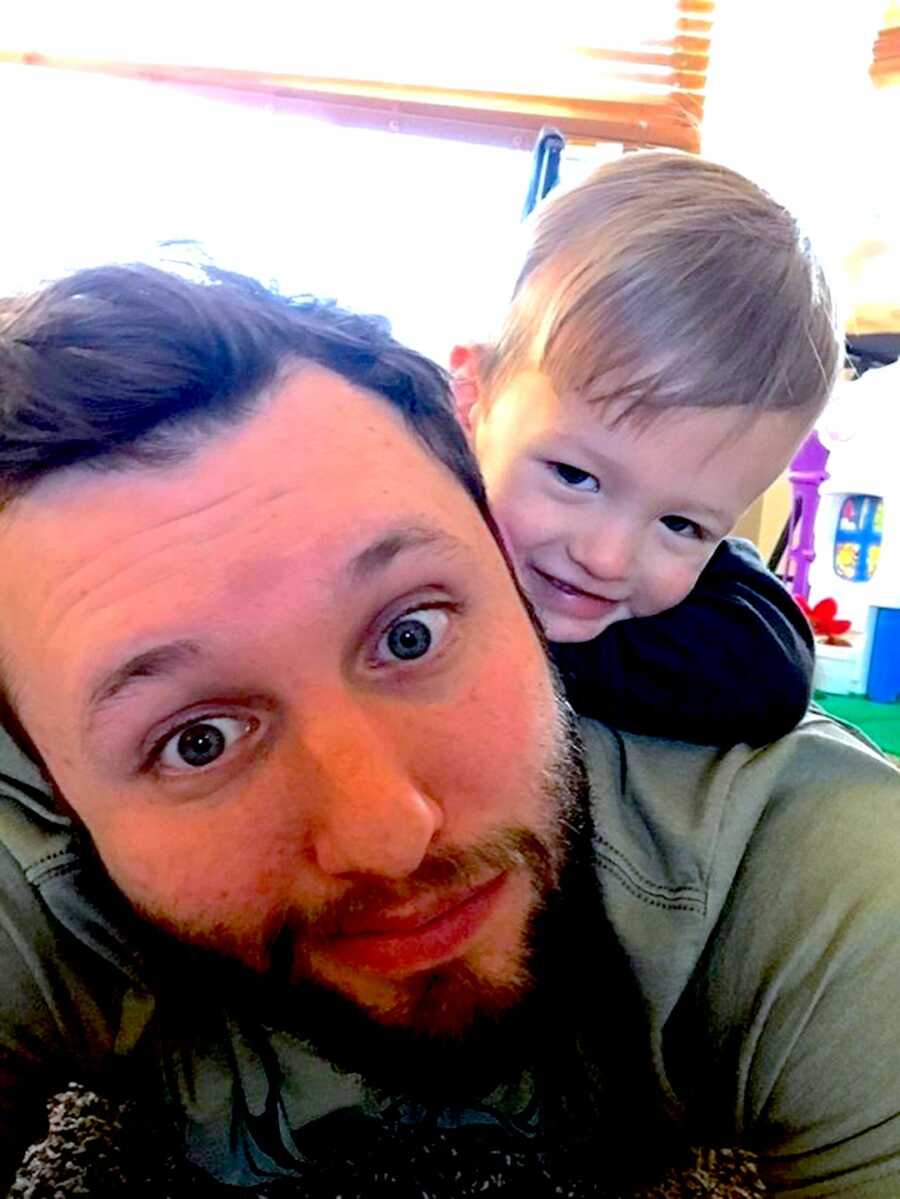 Dad lays on the floor with his son laying on his back