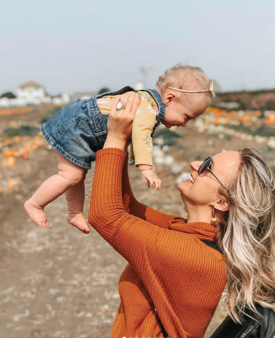 Woman holds her daughter up above her head