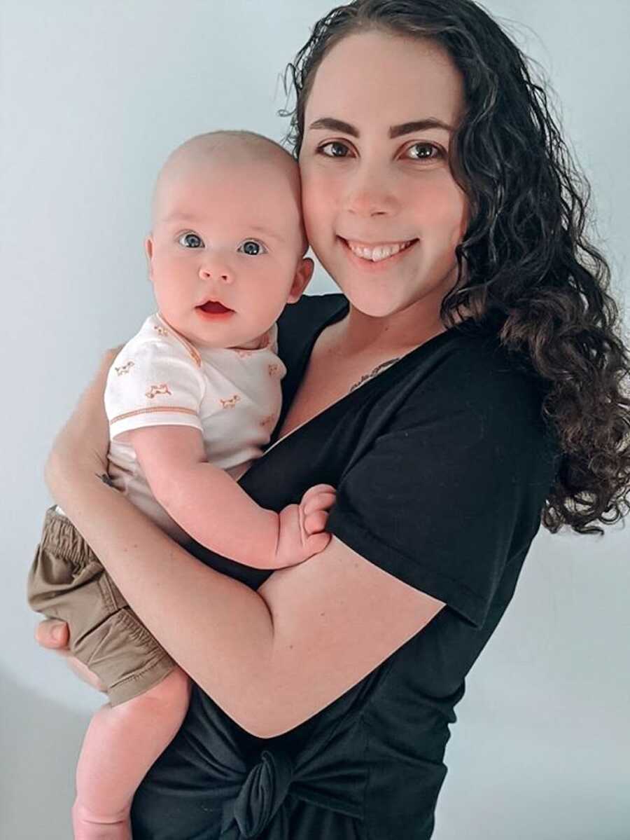 mom stands holding her baby