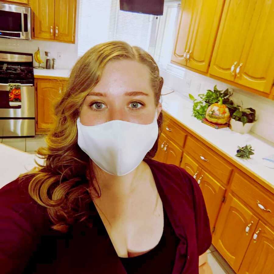 mom stands in kitchen wearing mask over face