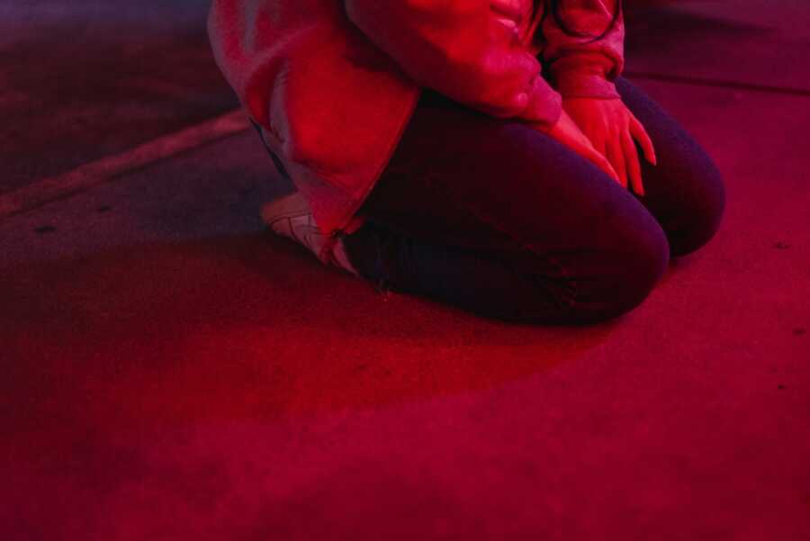 A woman kneels on the floor in the aftermath of a shooting