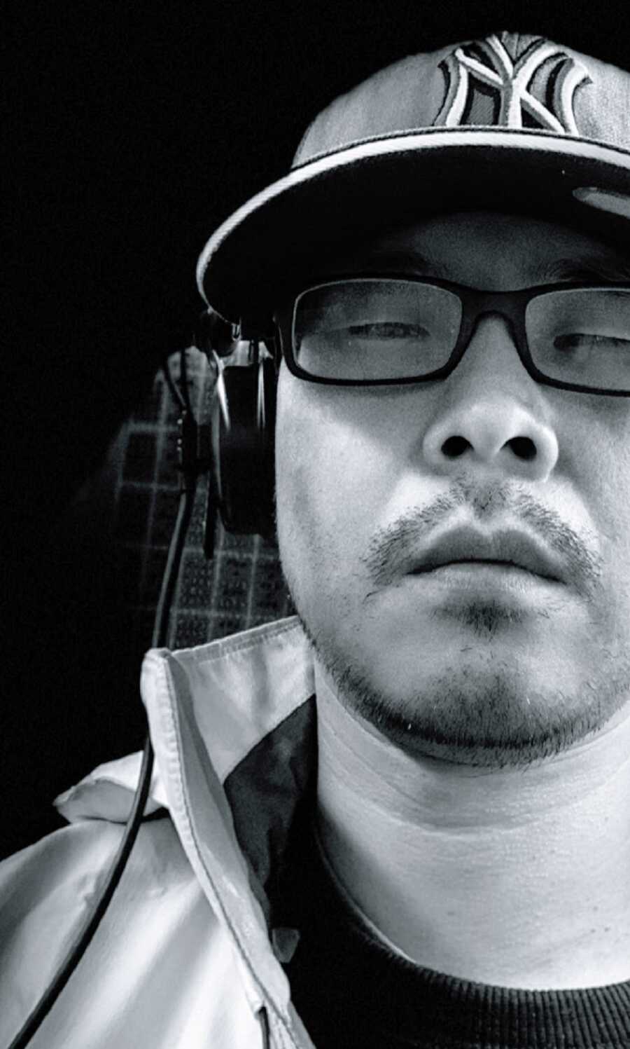 A visually impaired man wearing glasses and over-ear headphones