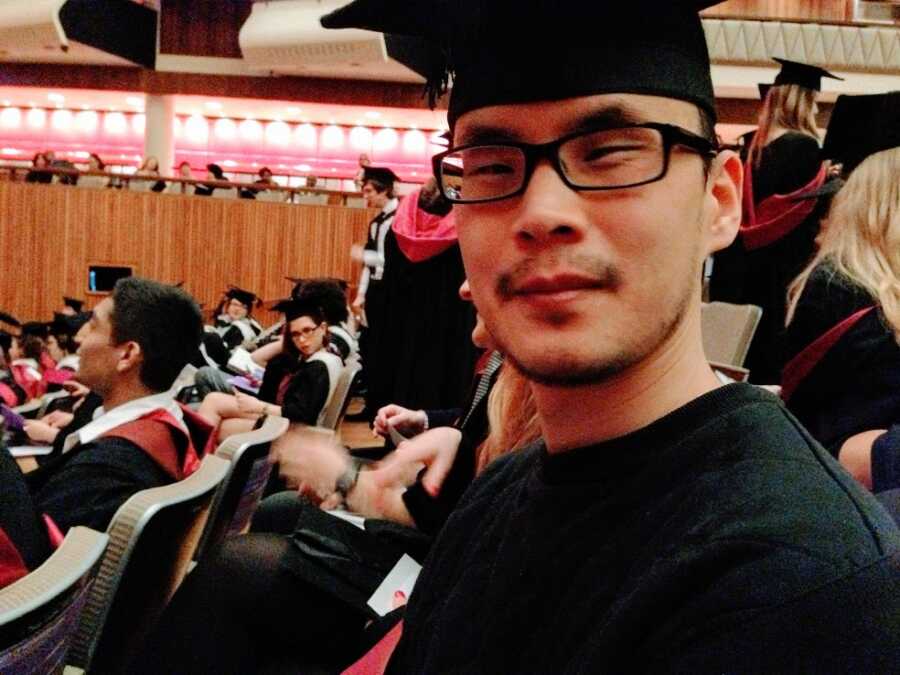 A man wearing a cap and gown at his graduation ceremony