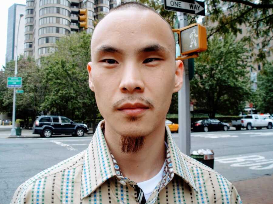 A man wearing a green and yellow striped shirt standing on a street corner