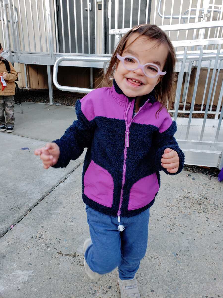 A little girl wearing a purple and black jacket