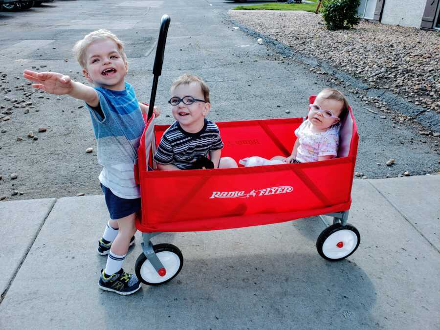 Three autistic siblings with a wagon, with the oldest boy holding the handle