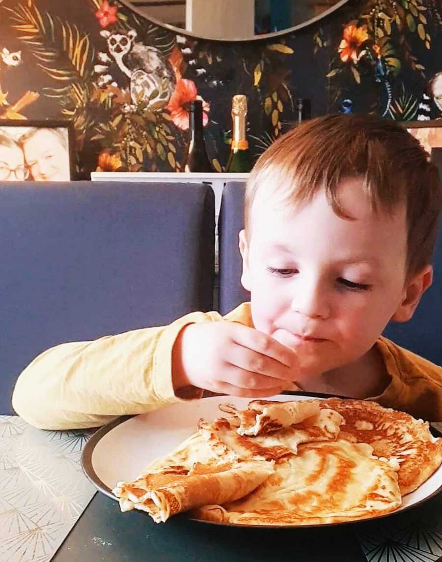 A boy with sensory aversion eating food off his plate