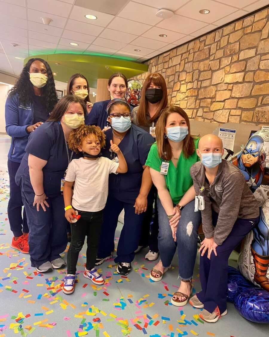 hospital staff with boy who is cancer free