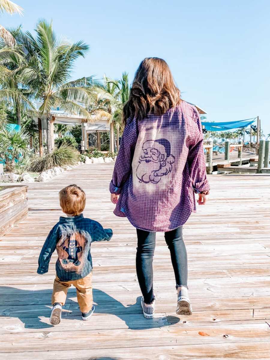 A mom walks with her young son on a boardwalk