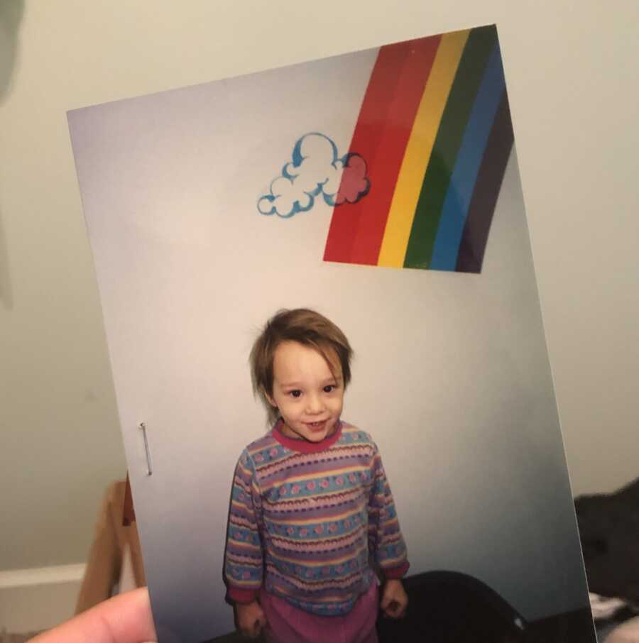Old picture of young foster girl with rainbow in the background.