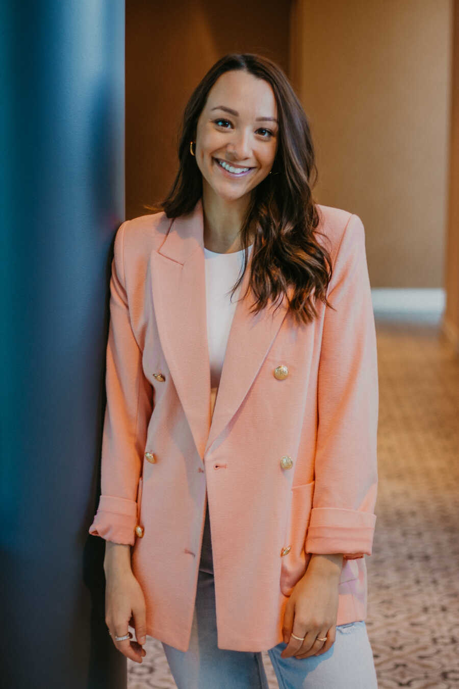 Woman wears pink blazer and takes professional photo.