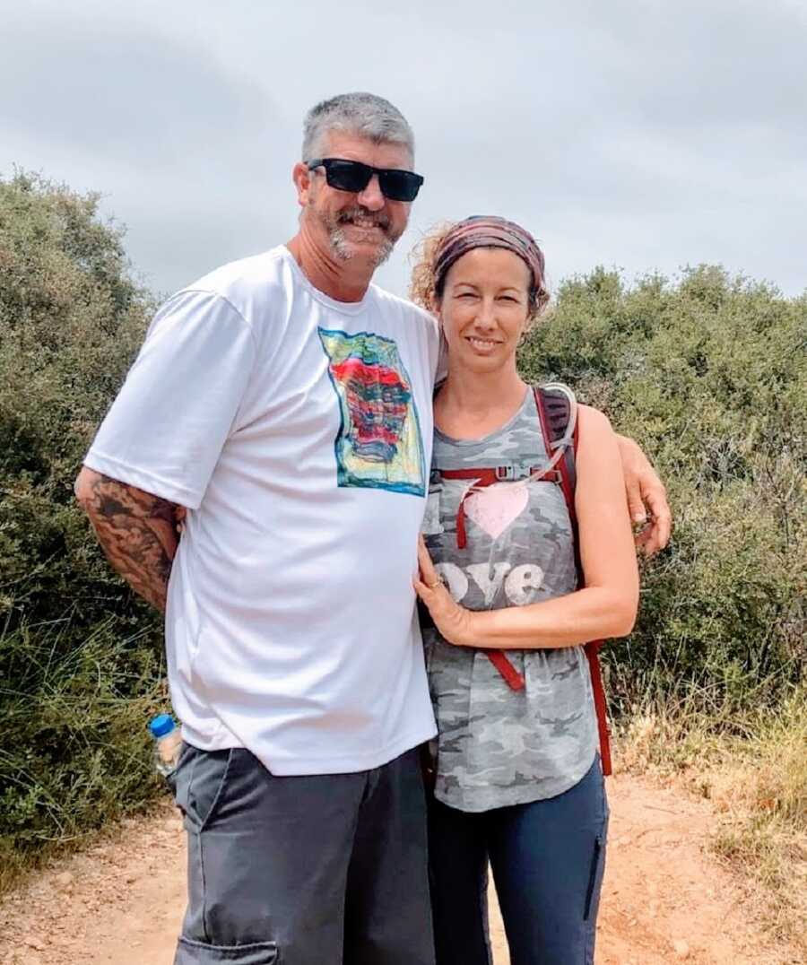 A woman and her husband stand together in a park