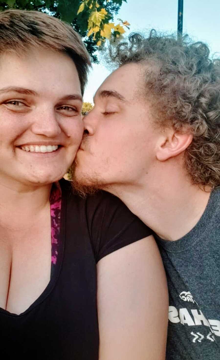 A young man kisses his girlfriend on the cheek