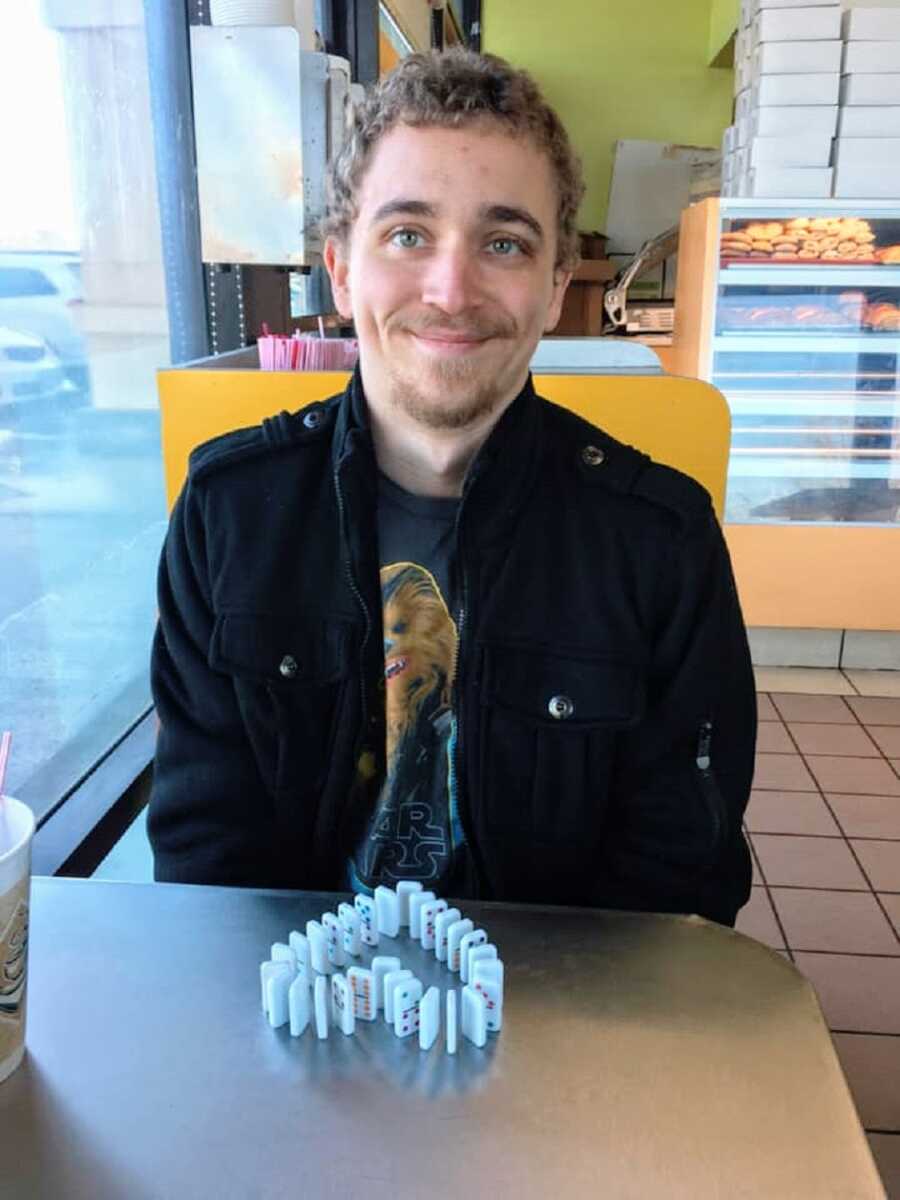 A young man with curly blond hair wearing a black coat and a Chewbacca shirt