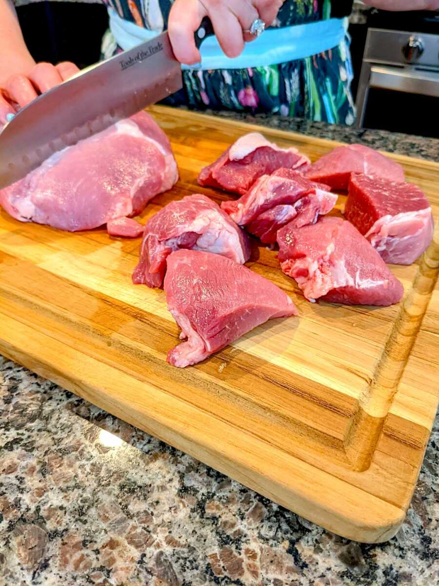 woman cuts pork butt into small pieces