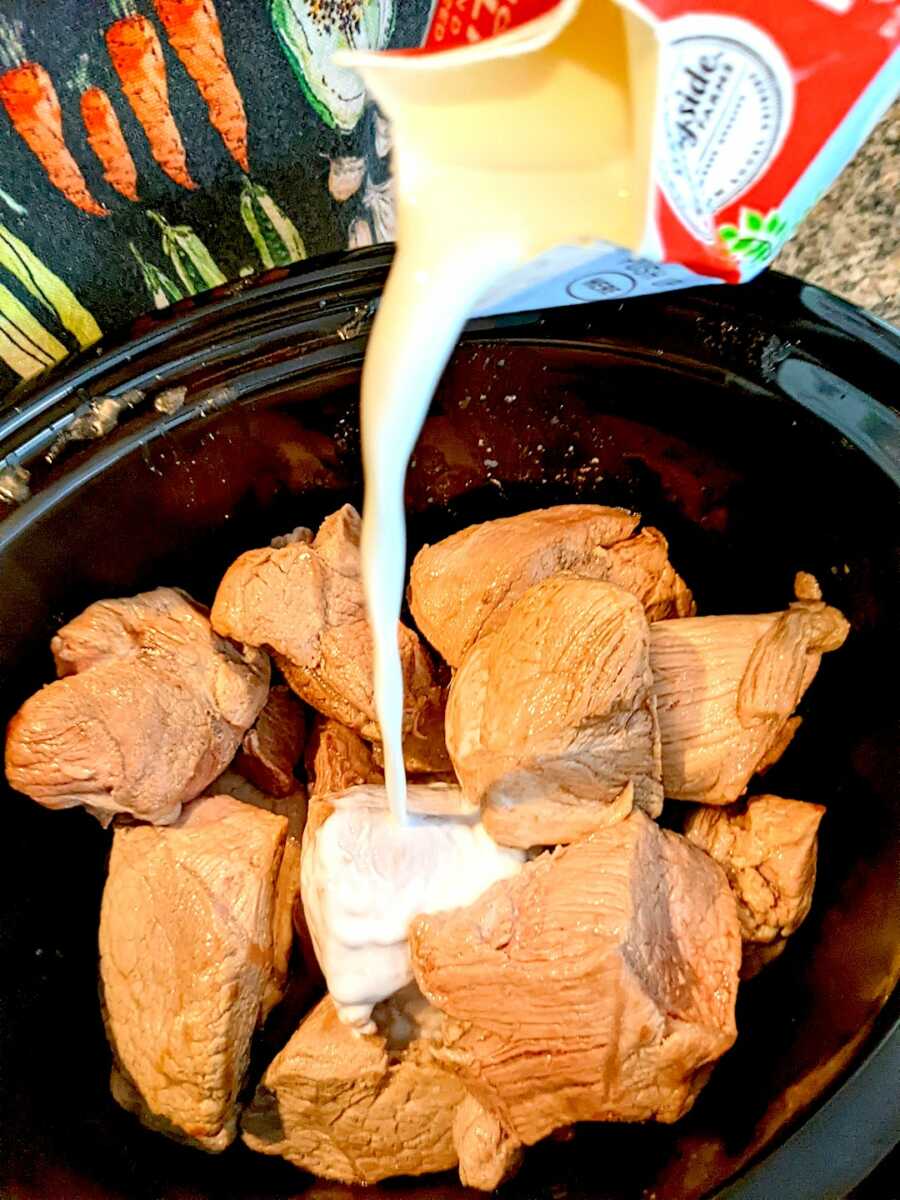 adding milk to the pork in the slow cooker