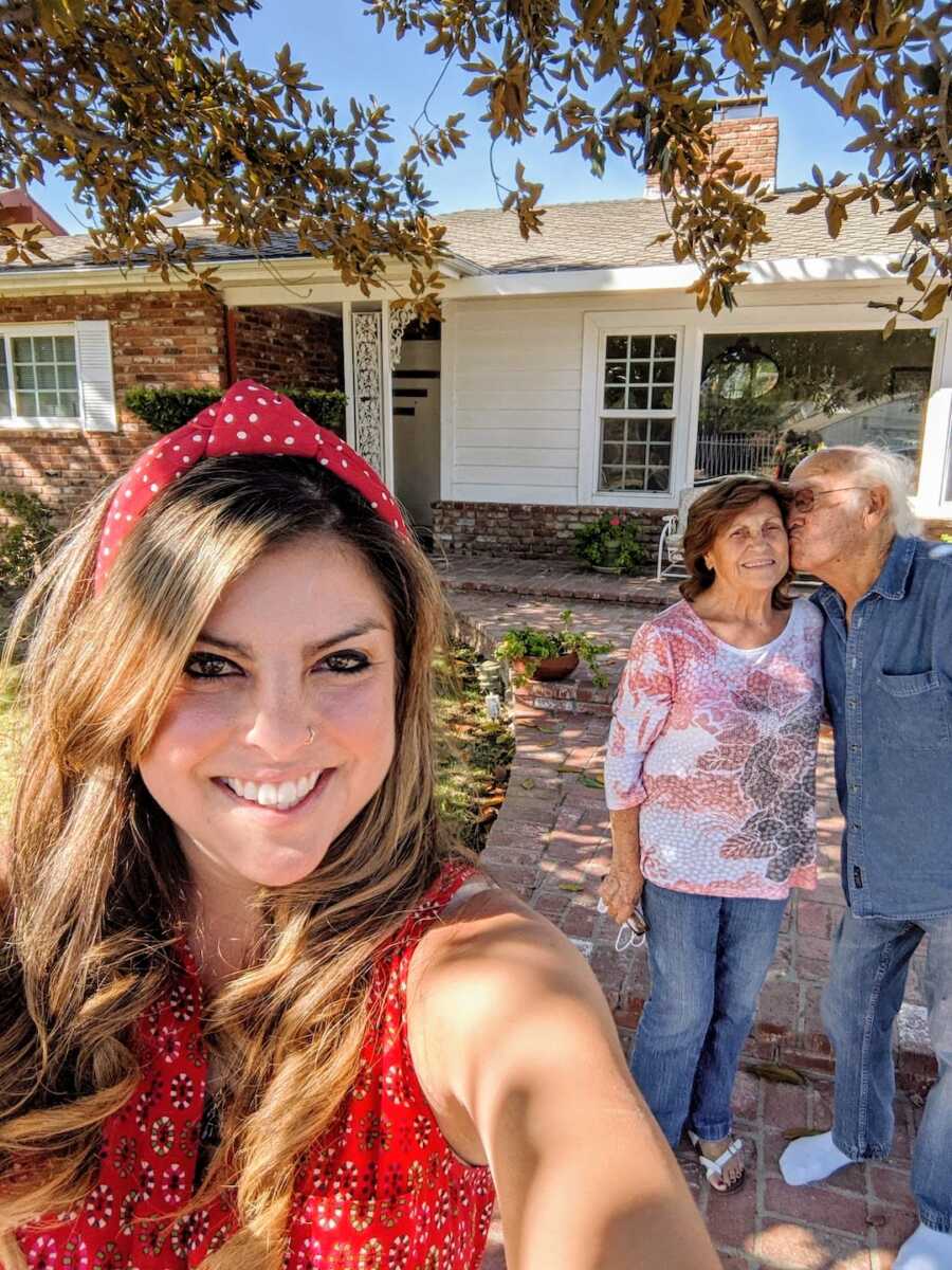 woman takes a selfie with her grandparents in the background