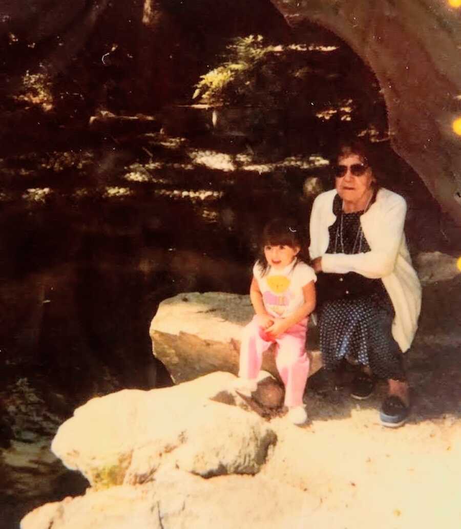 young girl sits with her grandmother on rocks
