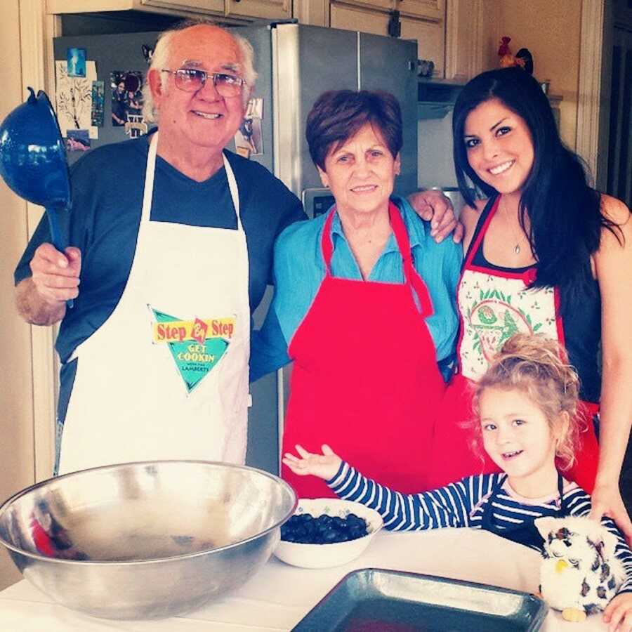 grandparents stand with their grandchild and great grandchild in the kitchen