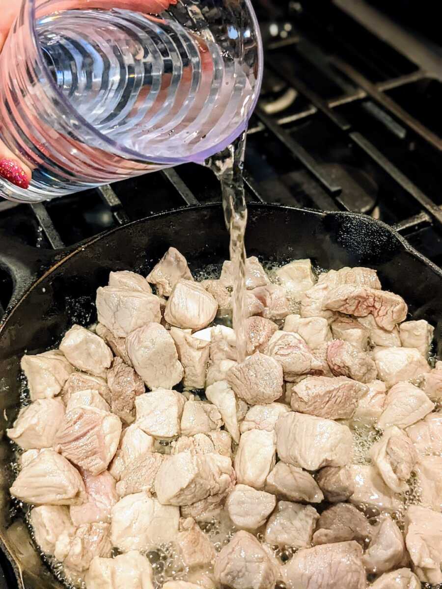 adding water to the pork as it is cooking
