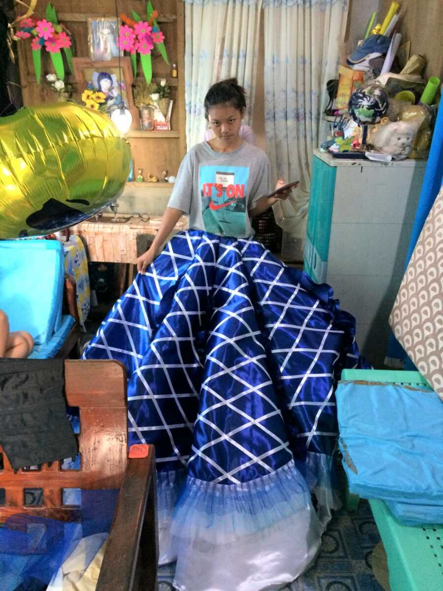 girl stands in skirt of prom dress as it is in progress