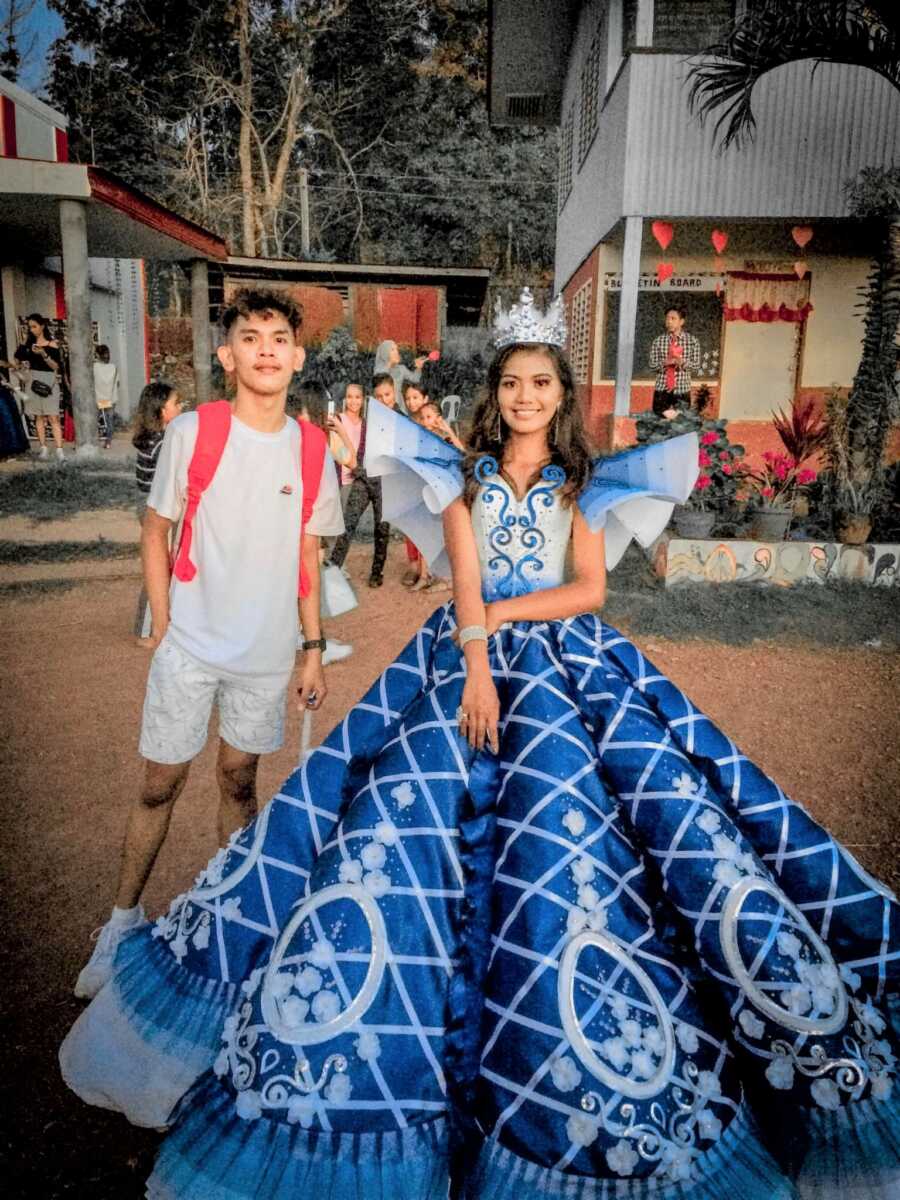 girl stands in her prom dress her brother made for her, he stands next to her