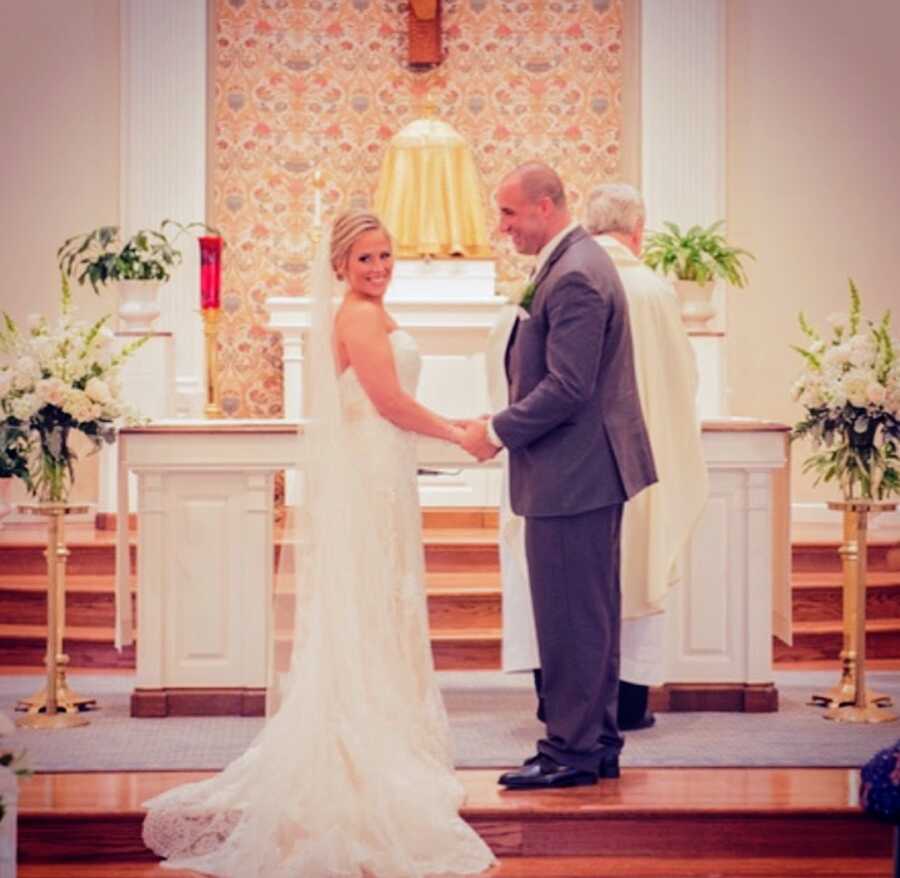 husband and wife stand at the altar holding hands