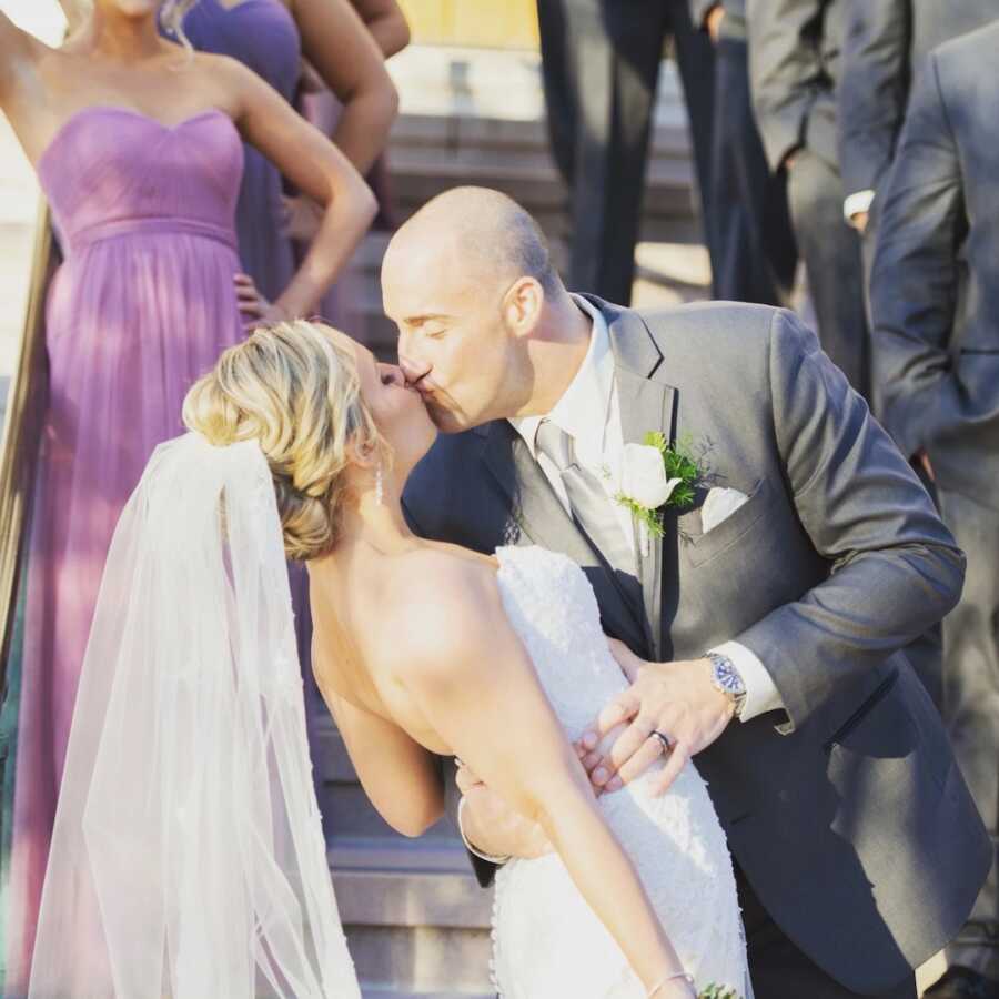 Husband tips wife back to give her a kiss on their wedding day