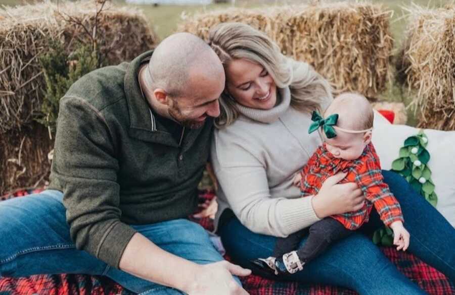 husband and wife sit together while she holds their baby on her lap