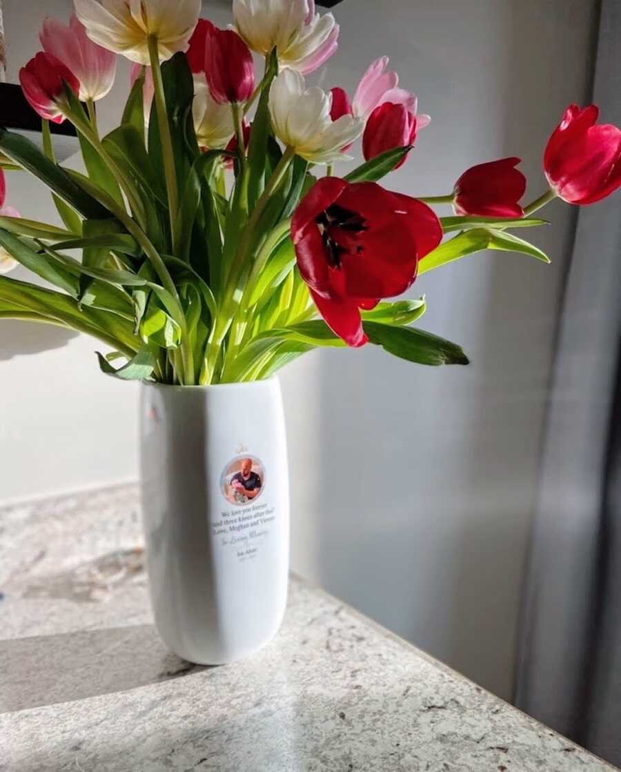 vase full of flowers sits on a counter