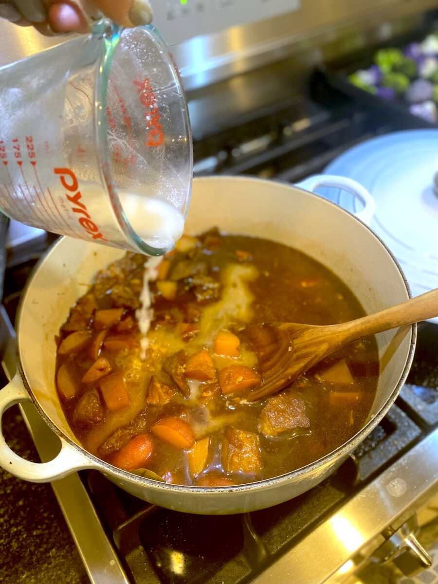Adding slurry into pot with adobo to thicken