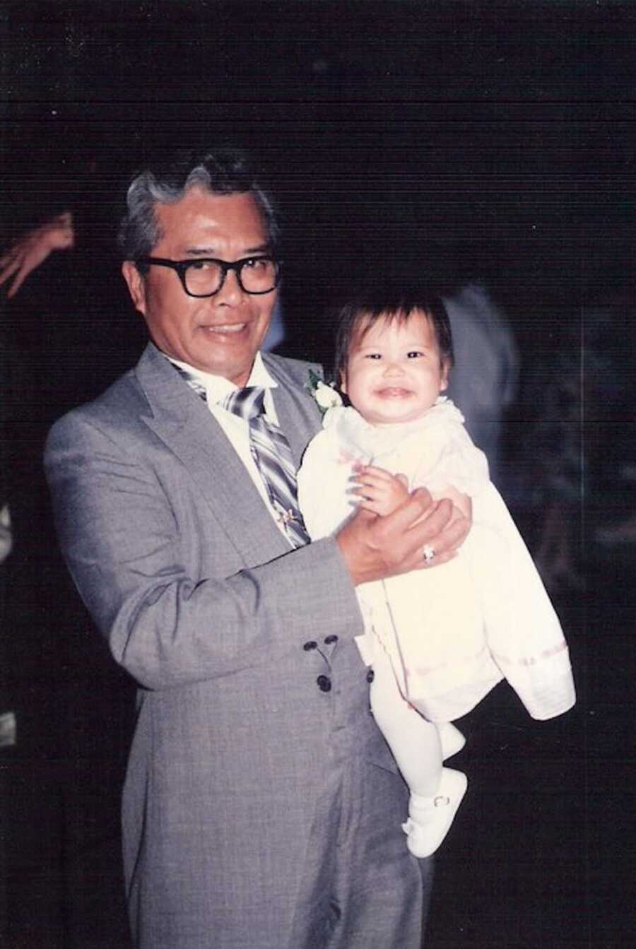 Grandfather holds his grandchild, both are smiling