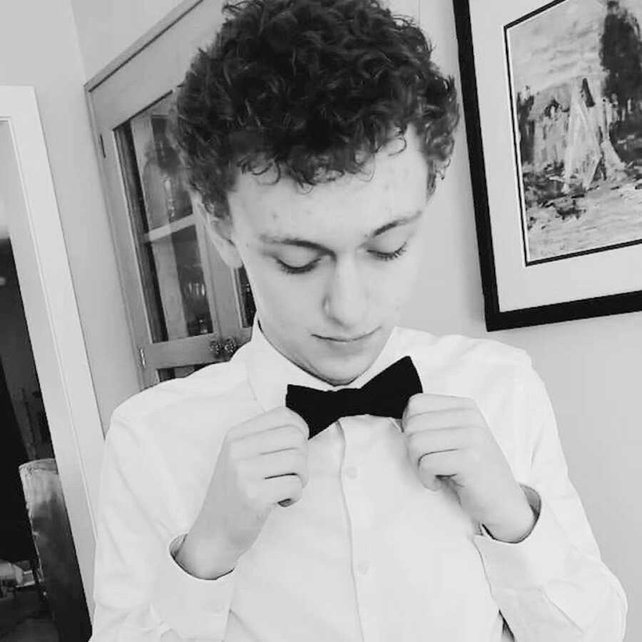 firstborn son looks down and adjusts his bow tie