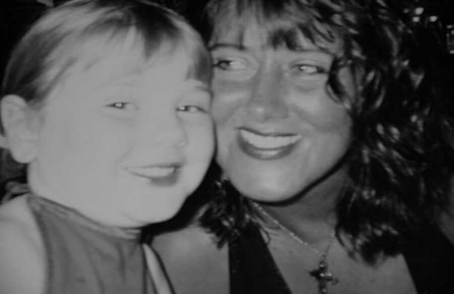 curly haired mom smiles next to her young daughter