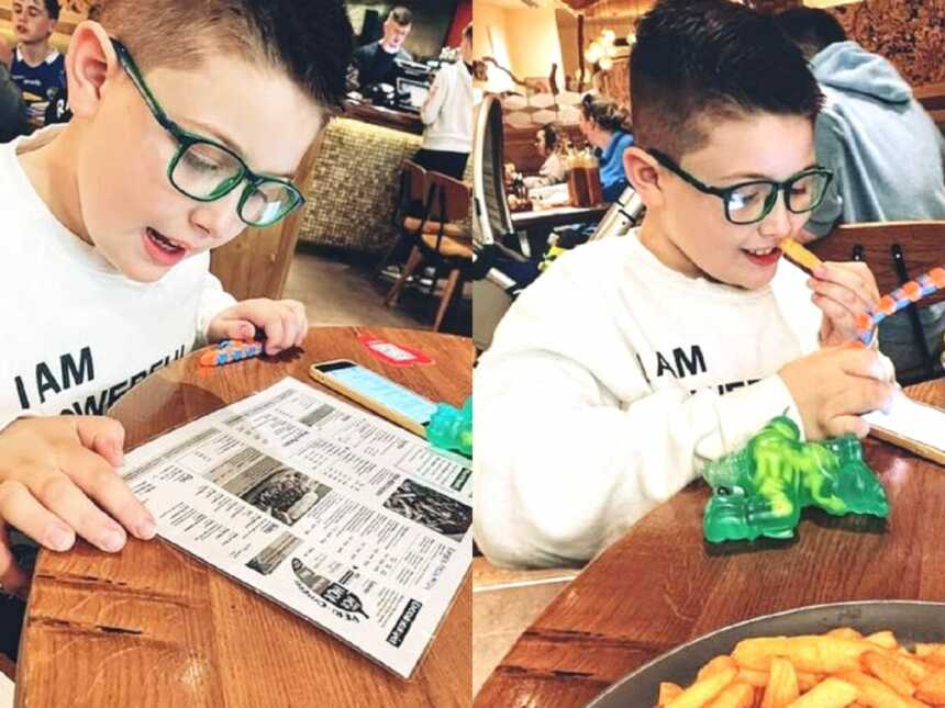 A boy reading a menu and eating fries at a restaurant