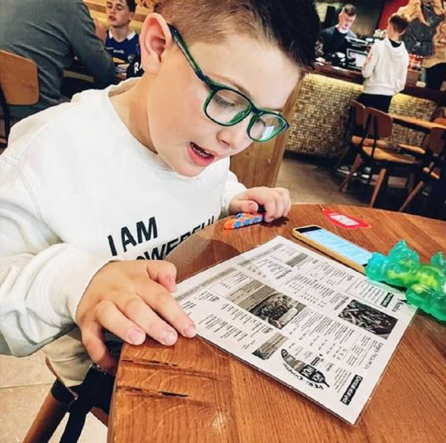 A boy with autism reading a menu at a restaurant
