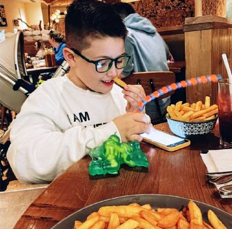 A nonverbal autistic boy eating fries at a restaurant