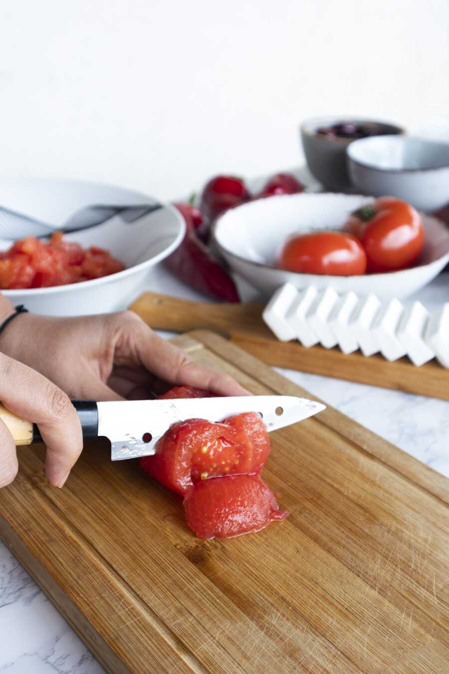 A woman chopping peeled tomatoes into cubes