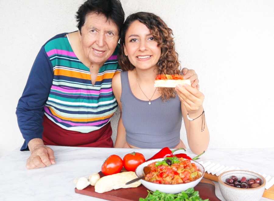 A young woman with her grandmother holding a slice of bread with pepper dip