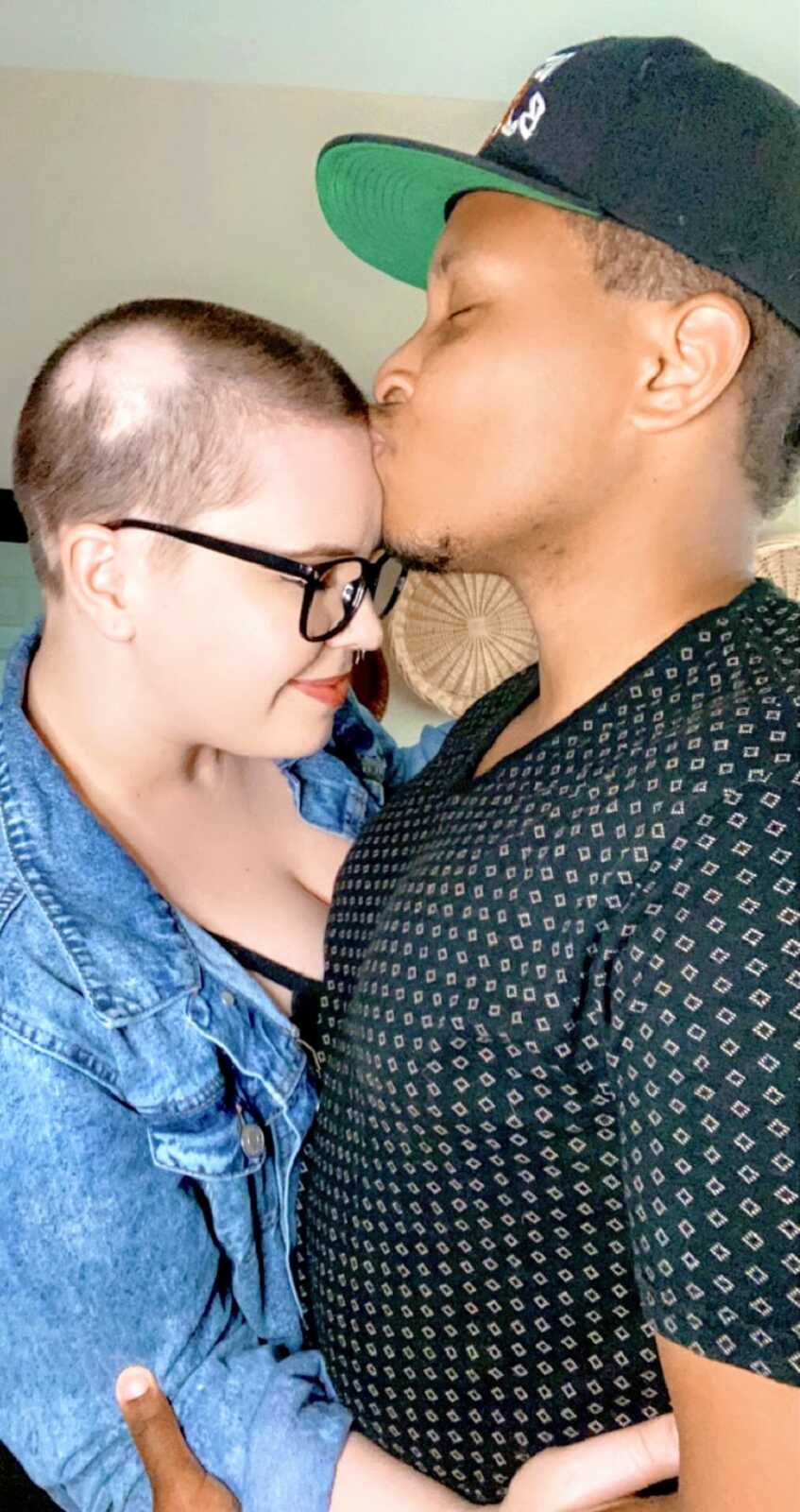 A man kisses his partner with alopecia on the head