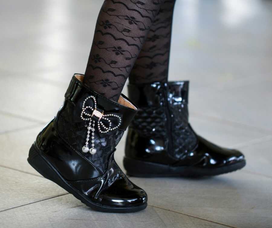 Toddler's shiny black boots with bows.